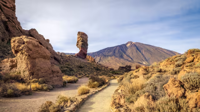 Panoramic view of Roque Cinchado, an unique rock formation with famous Pico del Teide mountain volcano summit in the background on a sunny day, Teide National Park, Tenerife, Canary Islands, Spain