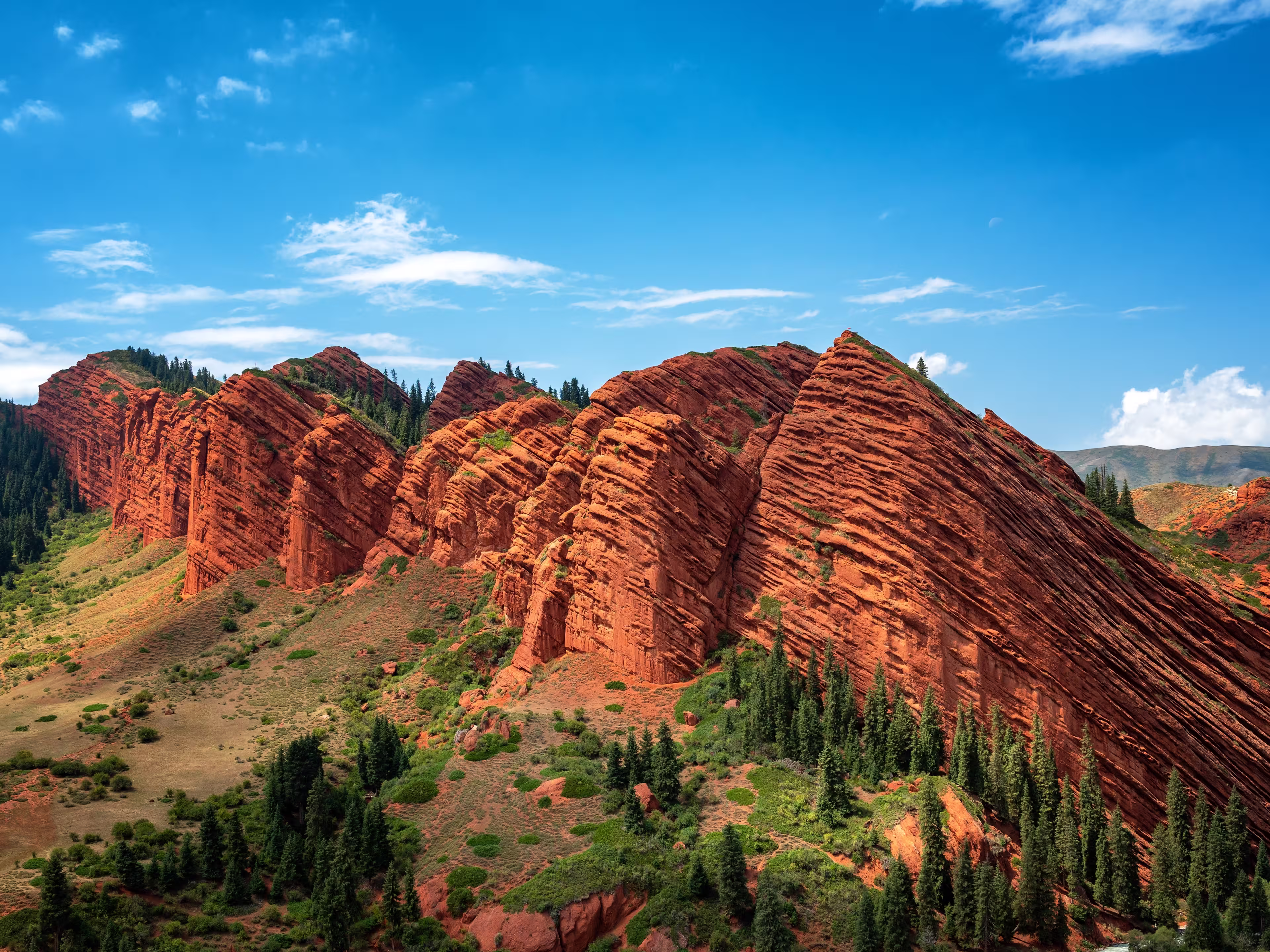 The Seven Bulls rock formations rise dramatically from the mountain landscape near Karakol, Kyrgyzstan, creating a striking natural landmark.