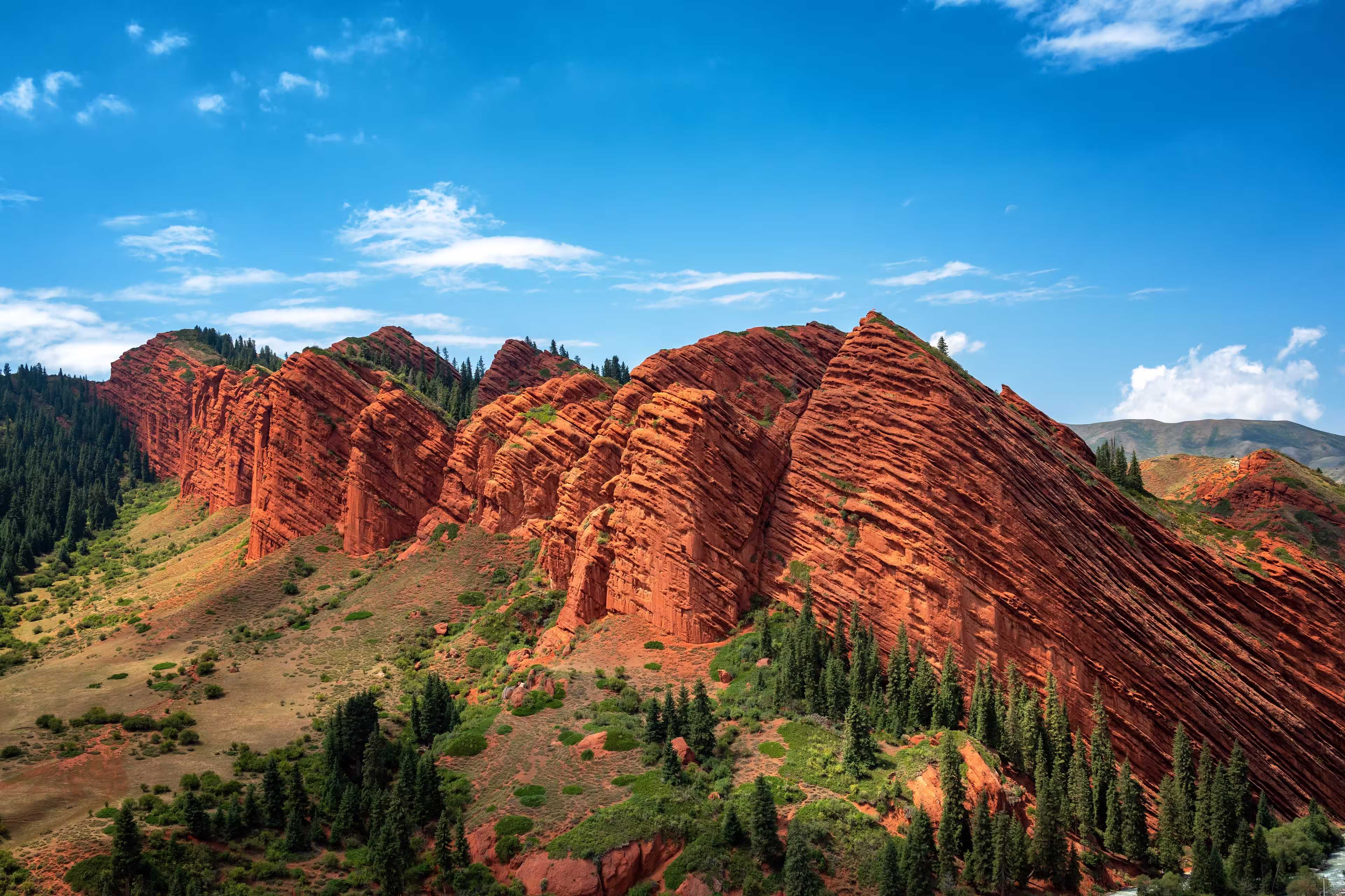 The Seven Bulls rock formations rise dramatically from the mountain landscape near Karakol, Kyrgyzstan, creating a striking natural landmark.