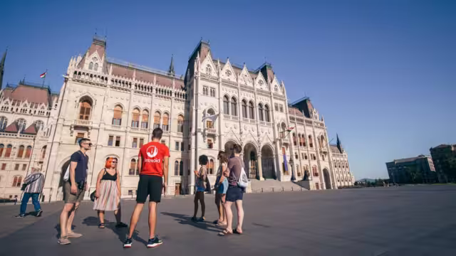 18 to 35s travellers listen to a talk from Intrepid leader outside Hungarian Parliament in Budapest on sunny day