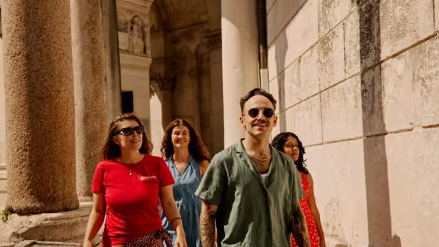 Traveller group and Leader smiling as they walk through Diocletian's Palace surrounded by cobblestone interior in Split, Croatia