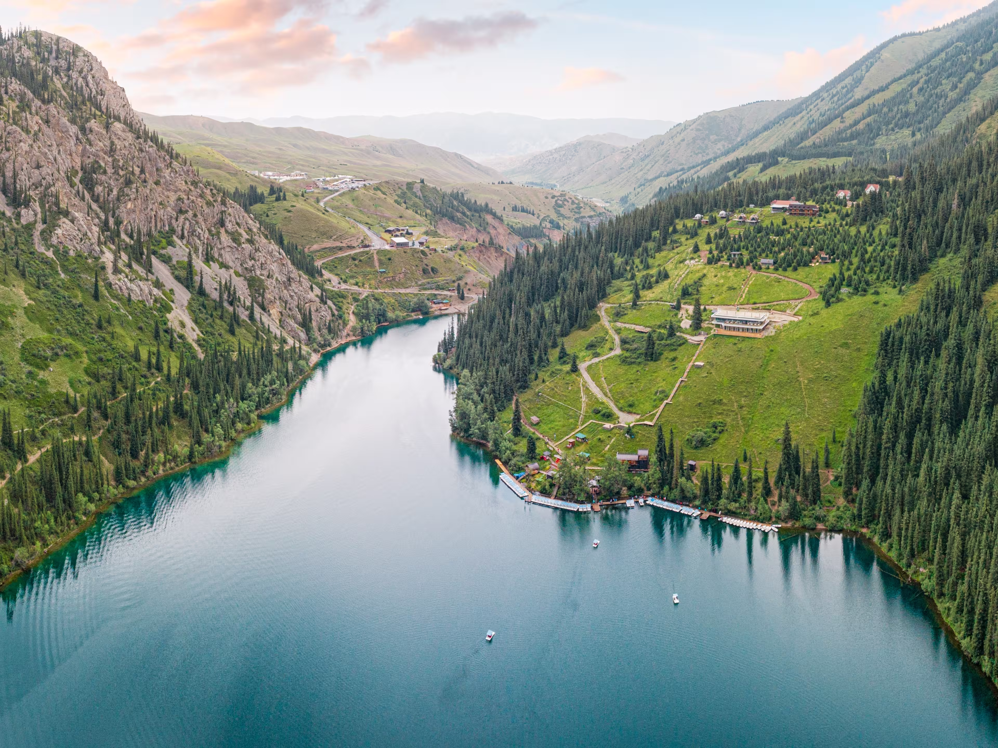 Aerial view of beautiful Kolsai Lakes reflecting colorful sky, mountains and green forest at sunset in Kazakhstan