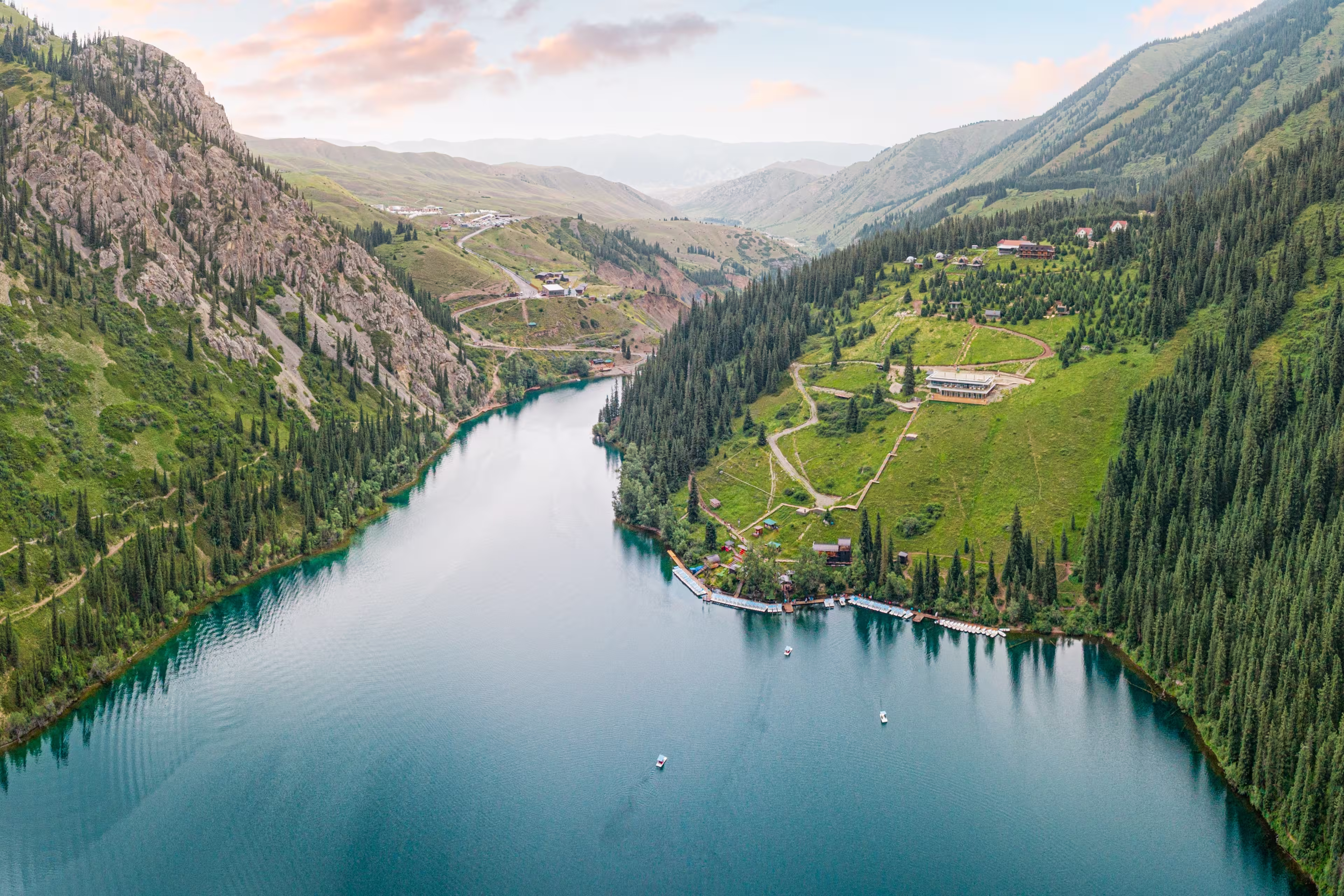 Aerial view of beautiful Kolsai Lakes reflecting colorful sky, mountains and green forest at sunset in Kazakhstan
