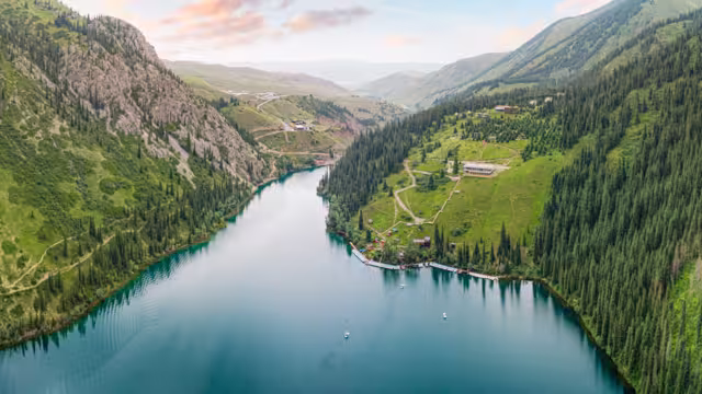 Aerial view of beautiful Kolsai Lakes reflecting colorful sky, mountains and green forest at sunset in Kazakhstan