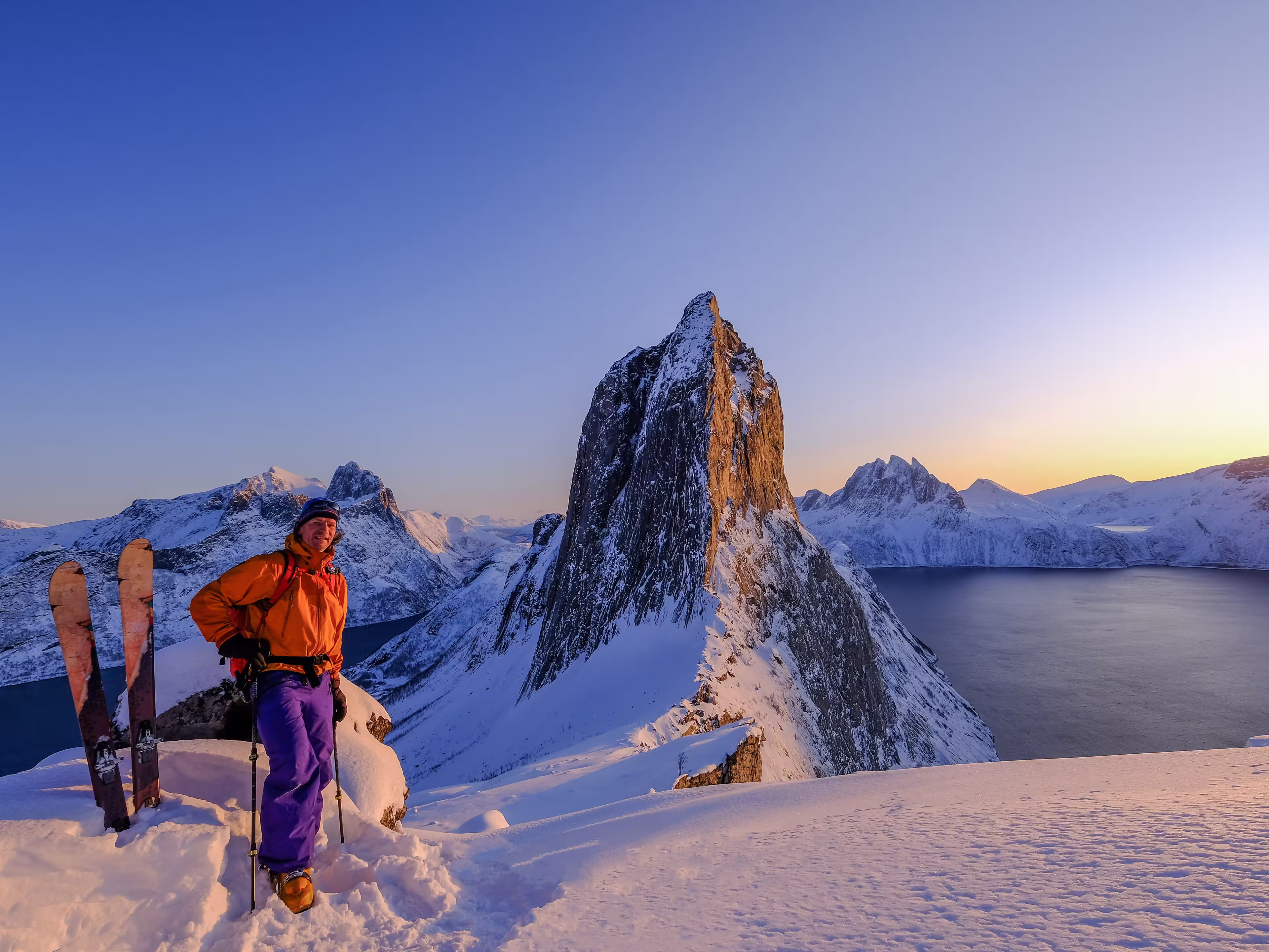 Skitouring man standing at the ridge in front of the iconic Segla mountain, view of the ocean fjords, Fjordgard, Senja, Troms, Norway, Europe