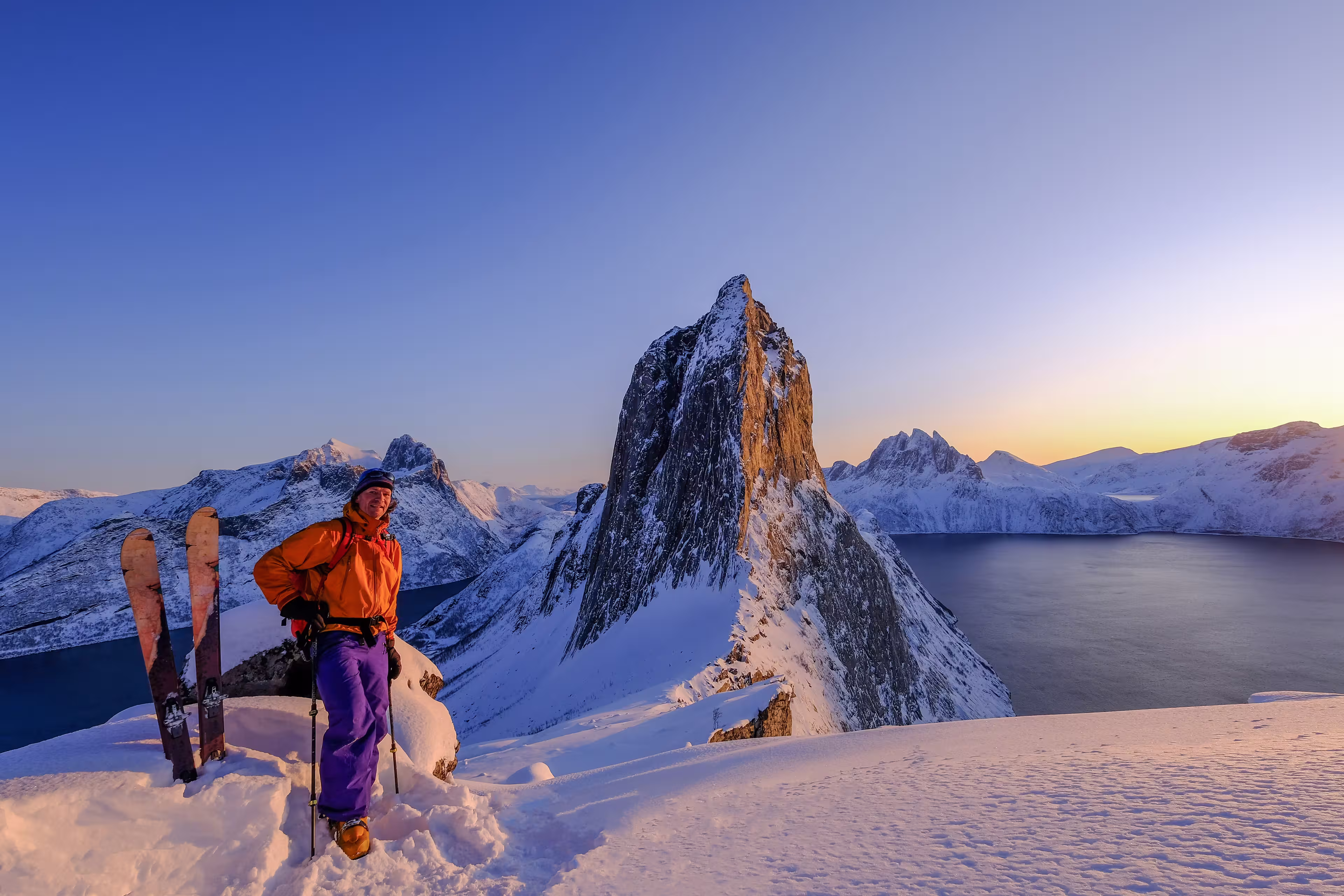 Skitouring man standing at the ridge in front of the iconic Segla mountain, view of the ocean fjords, Fjordgard, Senja, Troms, Norway, Europe