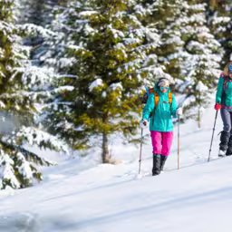 Two women walk through the snow on a winter hike, two in the mountains in winter, hiking equipment, snowshoes