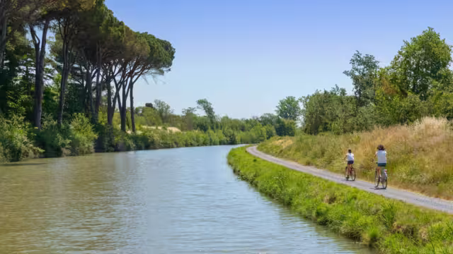Family on bikes, mother and daughter cycling by canal du Midi, active summer vacation in France