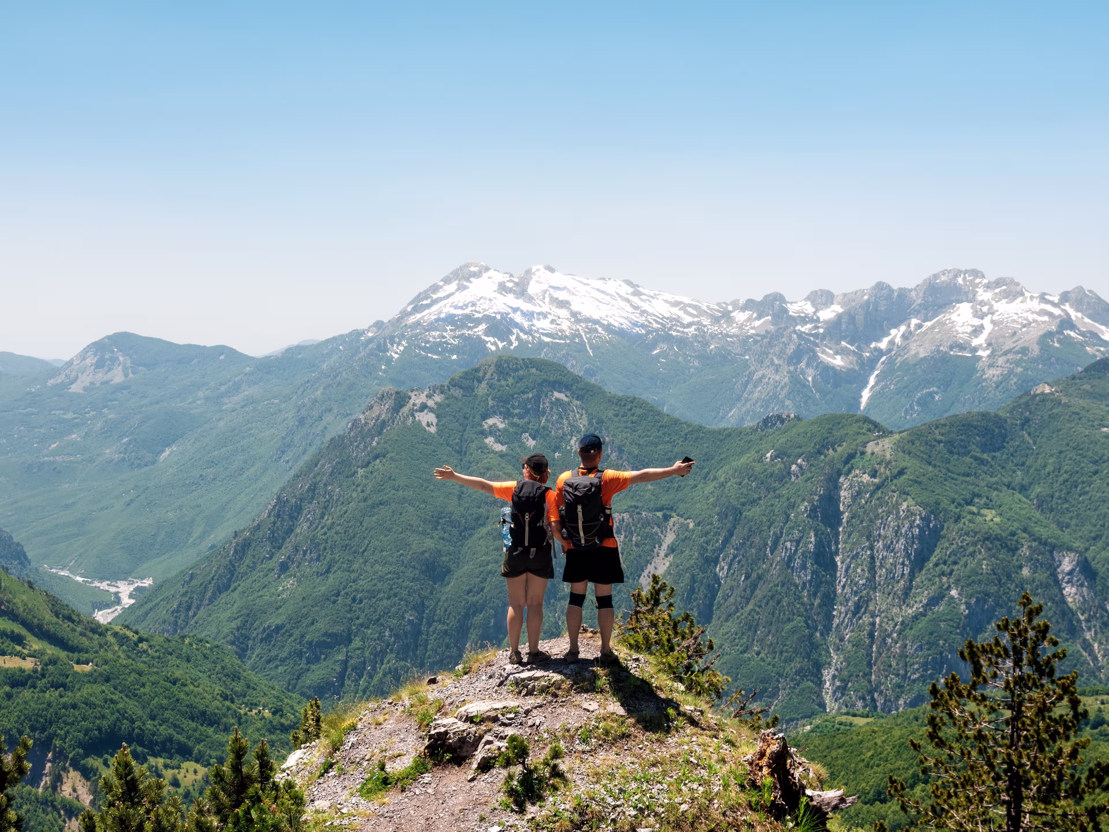 A couple of tourists rest on a meadow in the mountains of Albania. Mountains on the north Albania