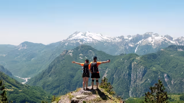 A couple of tourists rest on a meadow in the mountains of Albania. Mountains on the north Albania